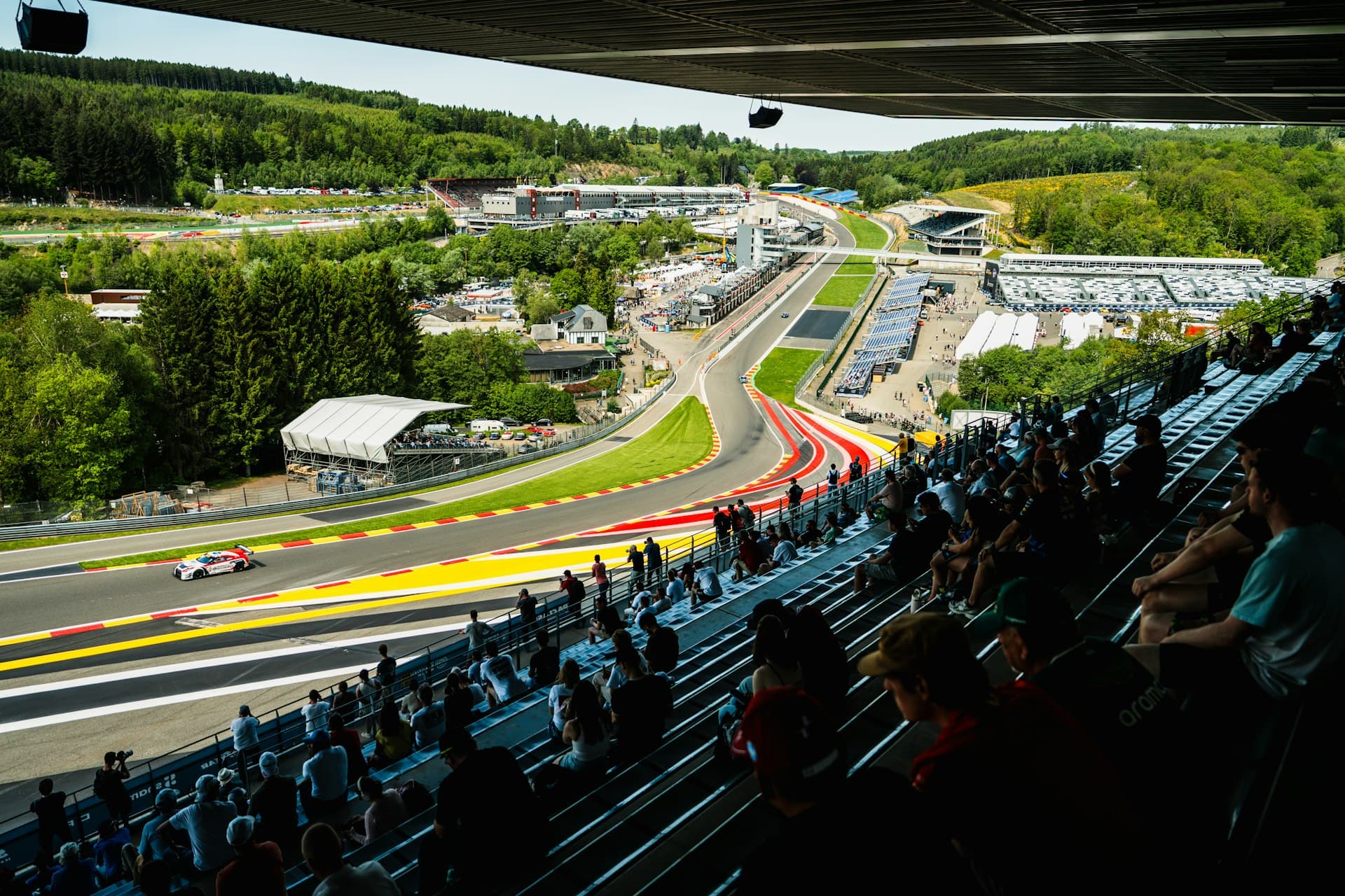 Spectators watching racing cars from the grandstands at a motor racing circuit