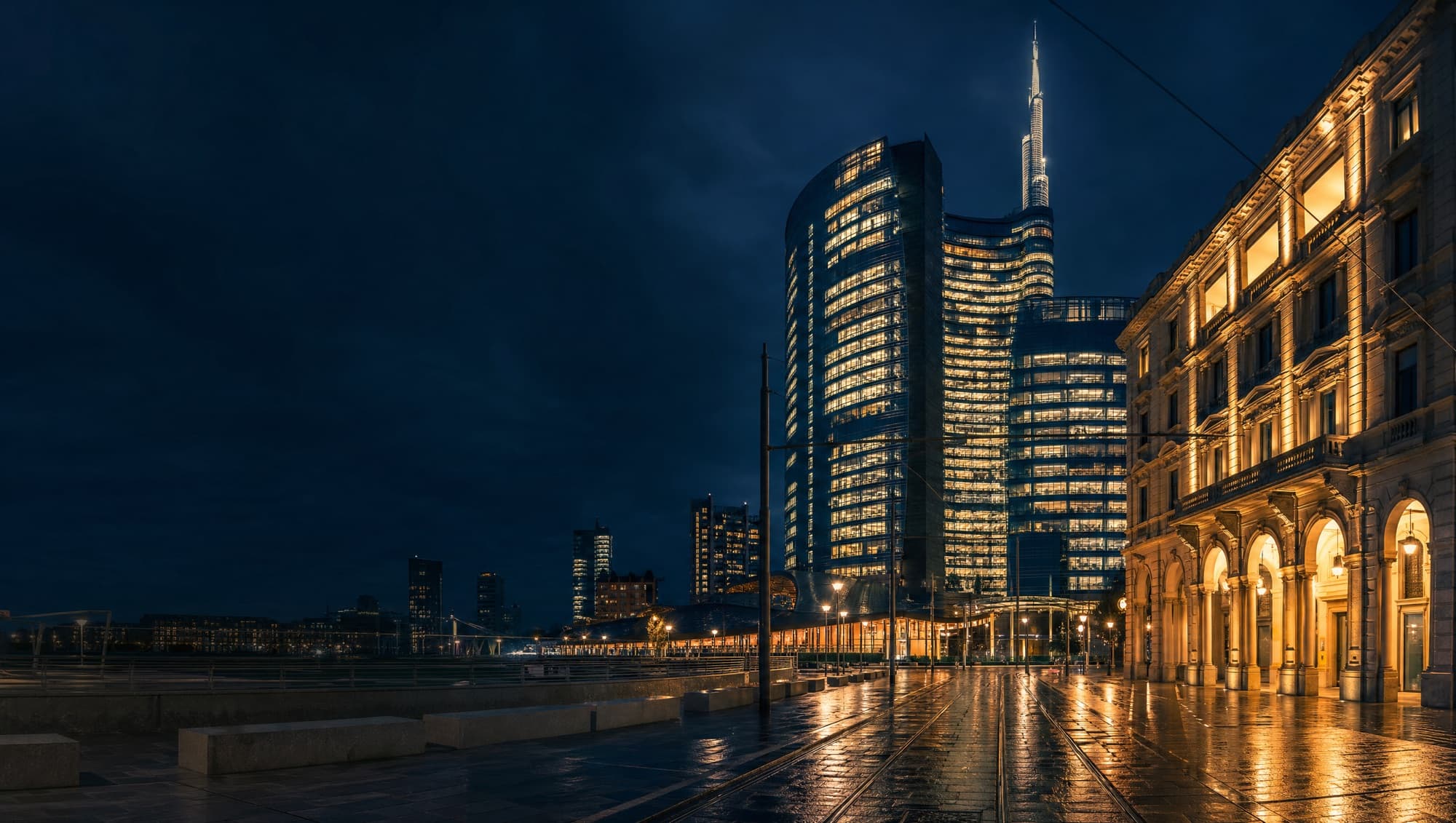 The lit towers of Milan’s Porta Nuova district above an empty piazza at night